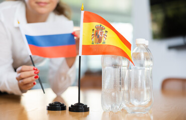 Little flag of Spain on table with bottles of water and flag of Russia put next to it by positive...