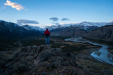 a man looking at the mountains during the blue hour