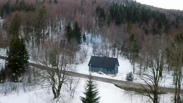 Aerial view of a small house along the road in the forest on the mountain with snow in wintertime, Mrkopalj, Gorski Kotar, Croatia.