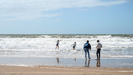 People having fun on the beach. Coast of North Sea in Hague. Tourists on sandy beach.