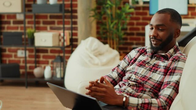 Patient in online consultation with psychologist, asking for advice in online meeting session, staying at home in cozy warm apartment living room. Man in relaxing video call with therapist