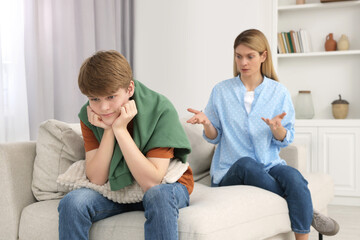 Teenage son ignoring mother while she scolding him at home - obrazy, fototapety, plakaty