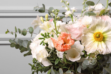 Obraz na płótnie Canvas Bouquet of beautiful flowers near light wall, closeup