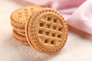 Tasty sandwich cookies with cream on beige background, closeup