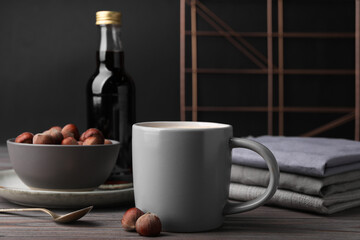 Mug of delicious coffee with hazelnut syrup on wooden table