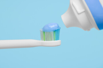 Fototapeta na wymiar Electric toothbrush with paste on light blue background, closeup