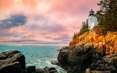 Sunset over the lighhouse on the cliff. Dramatic seascape with Bass Harbor Head Light Station in...