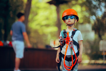 Girl Wearing Safety Equipment for Climbing in adventure Park. Brave child ready to climb on a rope...