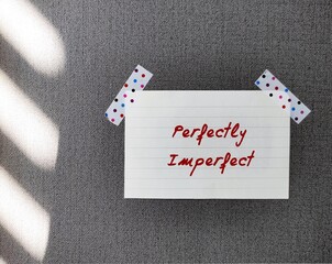 Stick note on wallpaper with handwritten text PERFECTLY IMPERFECT, concept of self acceptance, with...