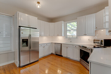 Interior of Modern White Kitchen with Stainless Steel Appliances and Stone Countertops