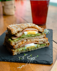 Superfood healthy sandwich with whole grain bread, avocado, egg, ham, cheese and sprouts of quinoa