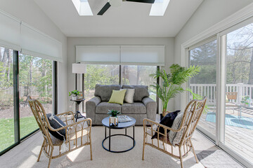 Spring Sunny Sunroom with Staged Furniture and Rattan Accent Chairs with Skylight and Patio Doors