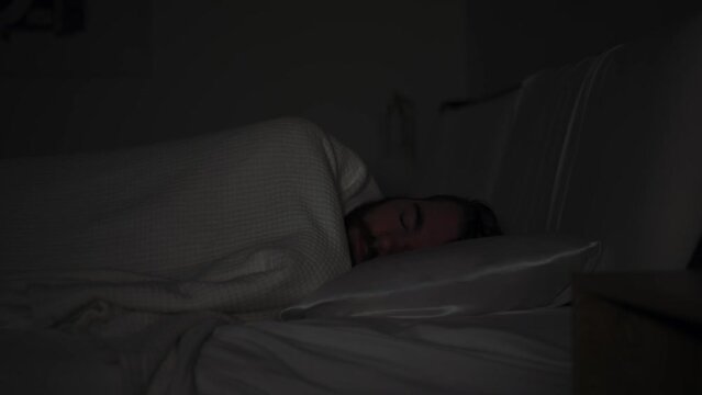 caucasian bearded man turning over while sleeping in bed at night, side profile