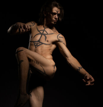 Naked handsome man with bodyart in the dark