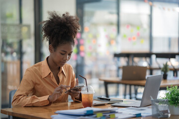 Focused young African female entrepreneur deep in thought while working at a table in a modern...
