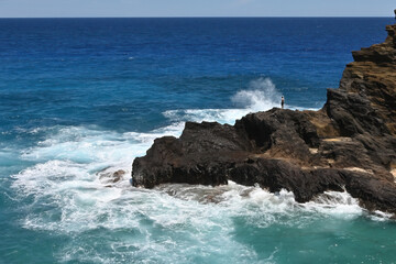 Emerald waves crash into the rocky shoreline on Oahu, Hawaii.