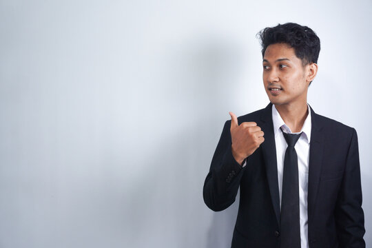 Young Handsome Asian Man Wearing Business Clothes Smiling And Looking At The Camera Pointing With Hands And Fingers To The Side.