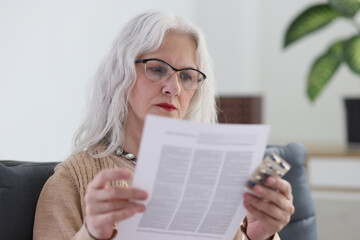 Senior woman in glasses reads instructions for medical drugs