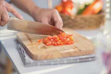 Cooking - Chef's hands are cutting tomatoes on the chopping board in the kitchen. Preparing pork stock with vegetables (broth) in a pot. Homemade bouillon recipe.