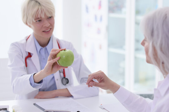 Dietitian advises senior woman eat fresh fruits in hospital