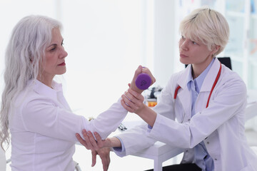 Doctor helps old woman to do recovery exercise for hand