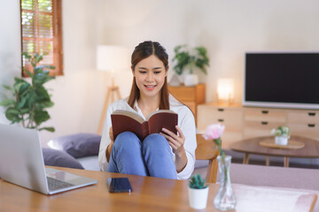 Working lifestyle at home concept, Women reading holy bible after working at modern home office