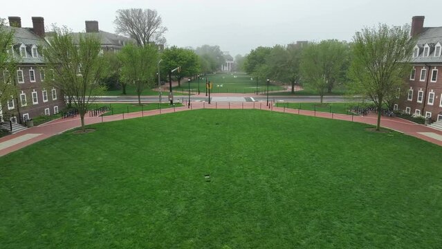 Aerial flyover academic lawns on foggy college campus. Green spaces for students to relax and colonial revival style dorms on foggy spring morning. Establishing shot at University of Delaware.