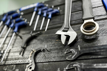 Fototapeta premium Wrenches and other hardware hanging on a tool board in a bicycle repair shop. Close up view with selective focus.