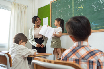 Female teacher teaching students in the classroom at school.