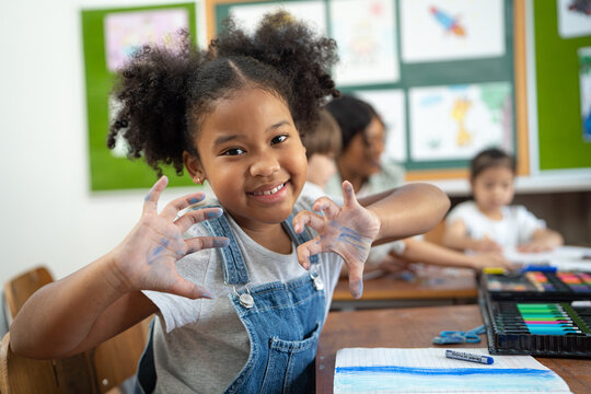 Little girl showing her hand to camera with smiling in classroom.