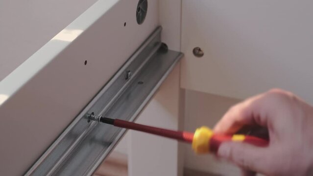 The furniture assembler assemble the interior furniture, close fixer sby screw and fixers, hands with a close-up
