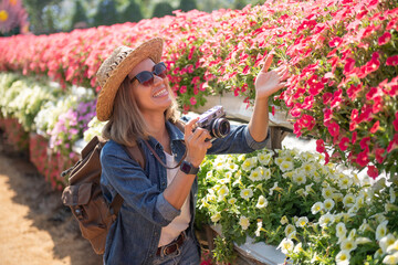 Beautiful woman enjoying flowers field, Portrait of Female photographer take photo outdoors on flower field landscape holding camera, woman hold digital camera in her hands. Travel nature photography