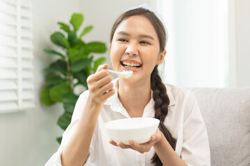 Healthy lifestyle, wellness food asian young woman hand use spoon eat tasty fresh organic yogurt, dairy product in bowl breakfast meal at home. Snack tasty on diet nutrition delicious natural yoghurt