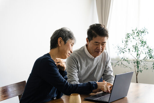 ノートパソコンを見る日本人シニア夫婦