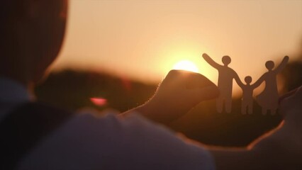 Side view of little girl holding paper family cutout on background amazing warm sunset or sunrise, family home, foster care, world mental health day, Autism support, budgeting cost of living concept