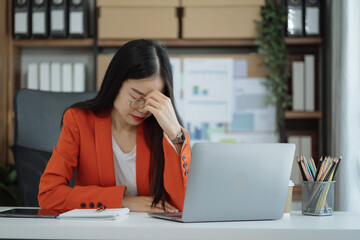 Young sad businesswoman is sitting at table, covering his face with his hand and talking on cell phone. On desk is laptop, tablet computer, Stress.