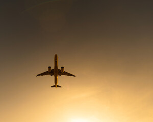 Bottom view of a flying plane at sunset. 