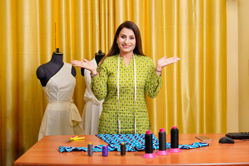 Confident indian female designer standing at shop.
