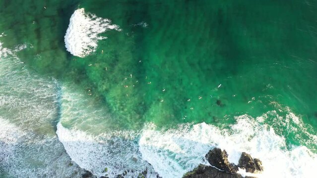 Aerial view over the ocean waves and surfers near the rocks below Norries Headland.
