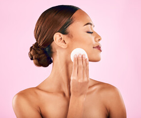 Woman, face and cotton pad in skincare for makeup removal or cosmetics against a pink studio...