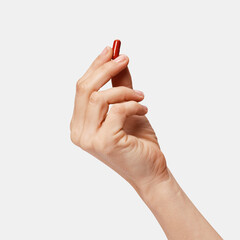 Hand holding a red capsule