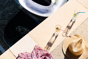 High angle view of lemonade glasses with dress and hat at poolside, copy space