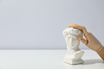 Wooden hand and ancient head on white table