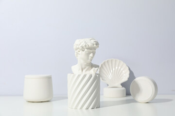 Cosmetic concept with ancient head on white table