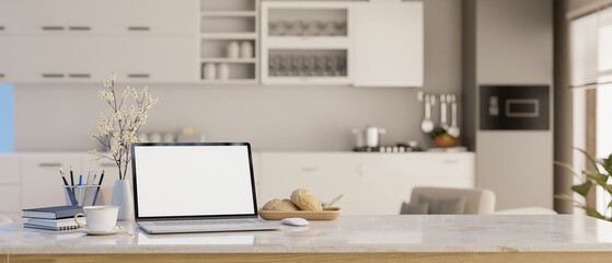 Workspace with white screen laptop computer mockup in modern apartment kitchen.