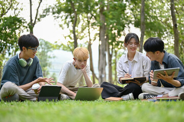 A group of diverse young Asian college students are doing a school project at the park together.