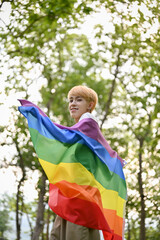 Portrait of an attractive and smiling young Asian gay man with an LGBT rainbow flag