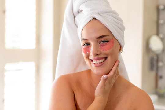 Smiling plus size caucasian woman with towel wrapped on head and red eye patches under eyes