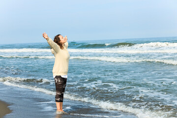 Young woman opening arms while walking on the white beach