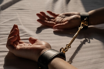 Close-up of woman's hands in leather handcuffs. Sex toy.